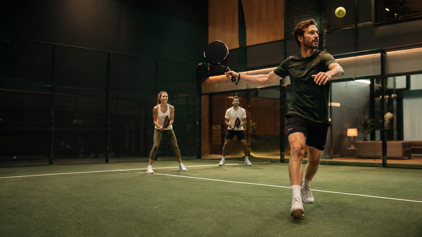 Padelspillere i aktion på en stemningsfuld indendørs padelbane